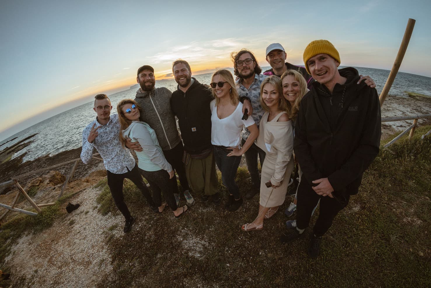 people in a group smiling with a sunset in the background